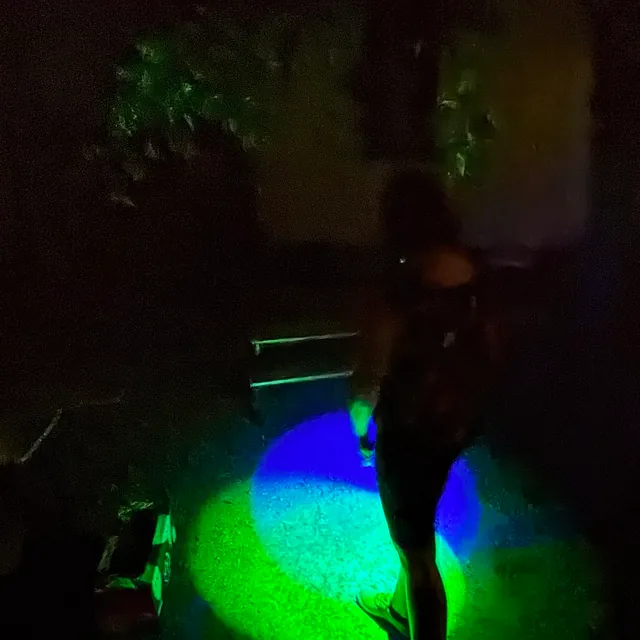 zu sehen ist eine Person, die im Dunklen mit verschiedenen Lichtquellen Farben mischt